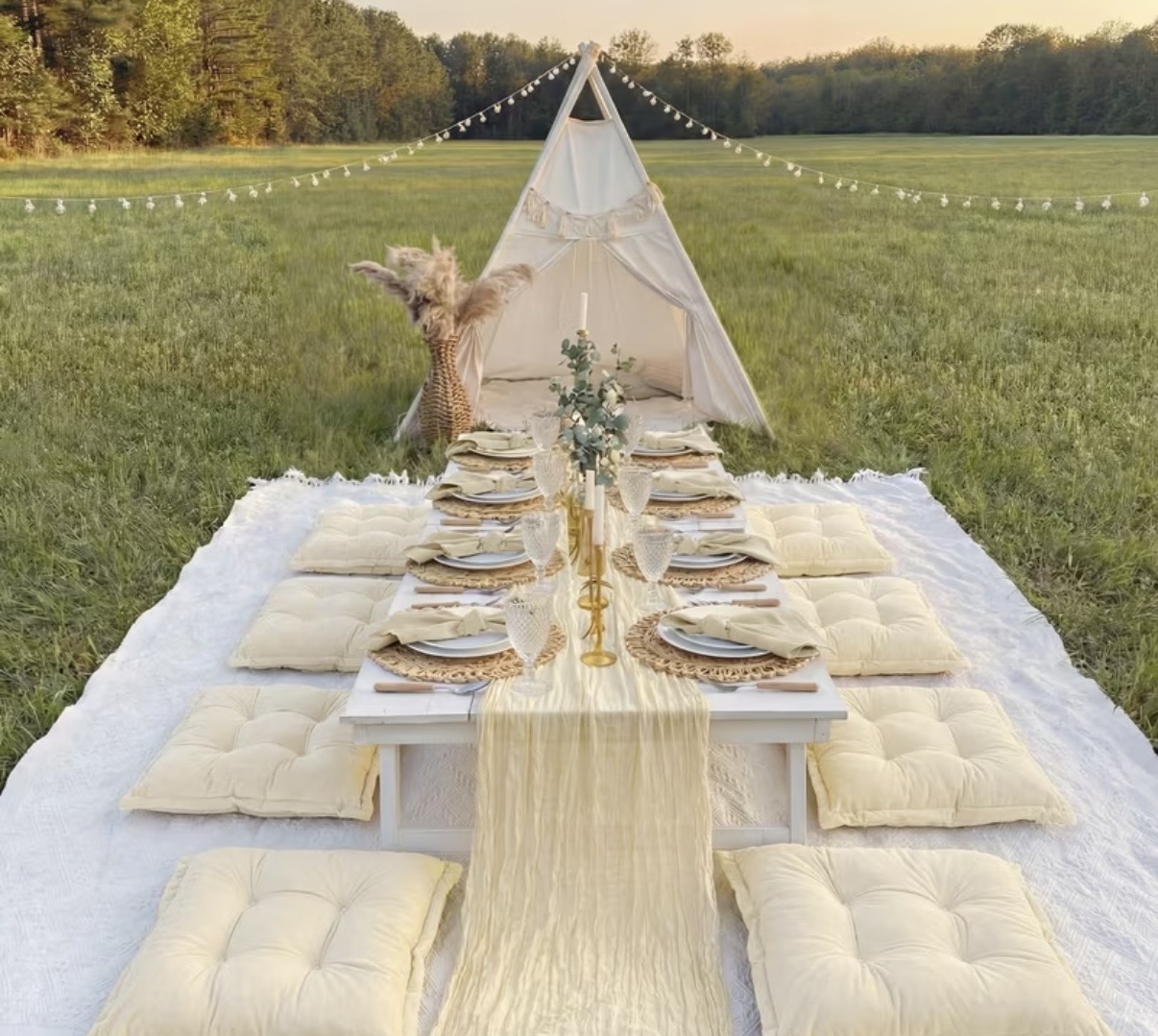 An elevated low-profile picnic tablescape styled with linen, gold accents, and florals